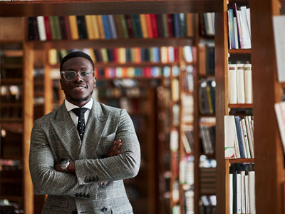 Person smiling and standing in front of library bookcases