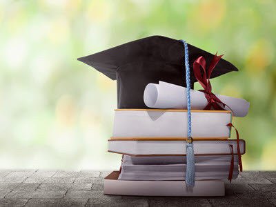 Stack of book with diploma and graduation cap on top