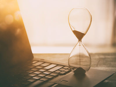 Hourglass beside laptop